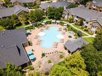 A bird's eye view of a residential area with a swimming pool surrounded by houses and trees.